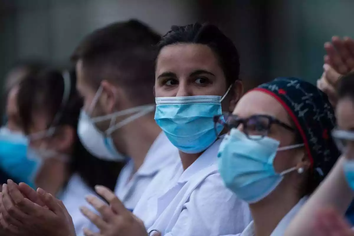 Varios sanitarios con mascarilla puesta aplaudiendo durante la pandemia de la Covid-19