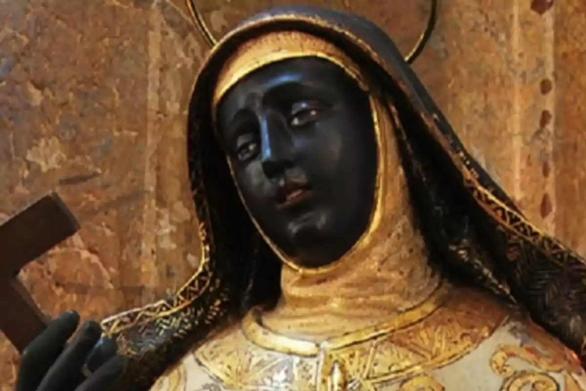 Estatua religiosa de una figura con rostro oscuro y vestimenta dorada sosteniendo una cruz. Estatua religiosa de una figura con rostro oscuro y vestimenta dorada sosteniendo una cruz.