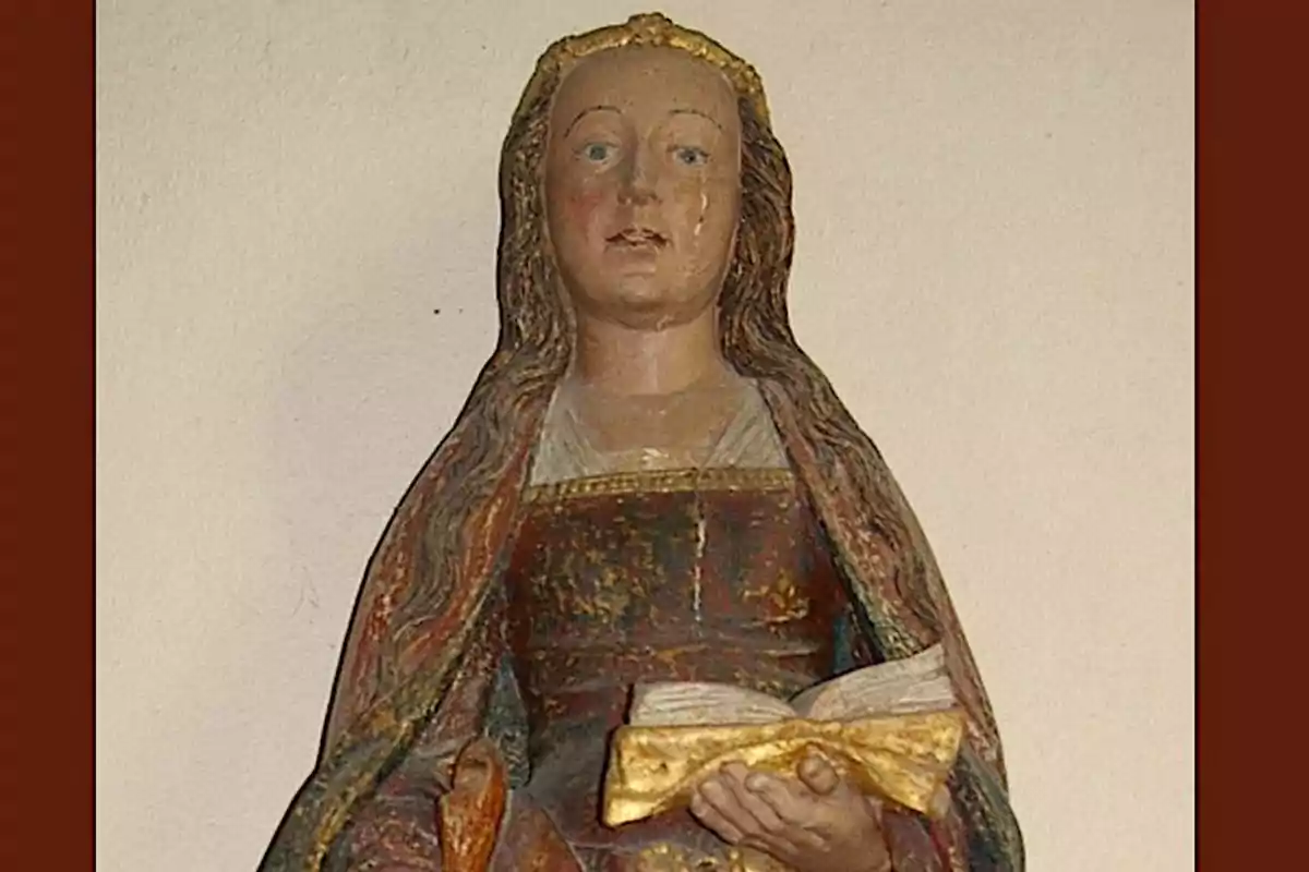 Escultura de una figura femenina con cabello largo y suelto sosteniendo un libro abierto en sus manos.