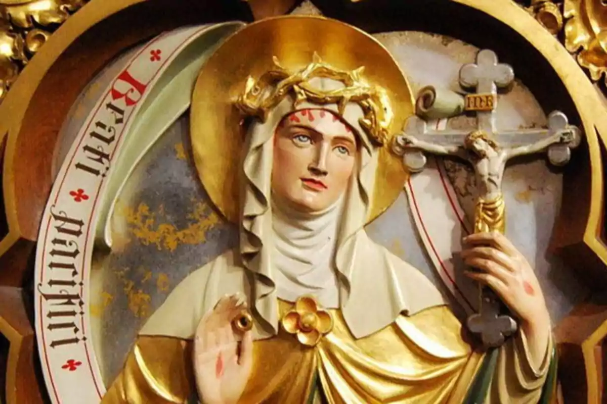 Una escultura religiosa de una figura femenina con aureola dorada, corona de espinas y un crucifijo en la mano. Una escultura religiosa de una figura femenina con aureola dorada, corona de espinas y un crucifijo en la mano.