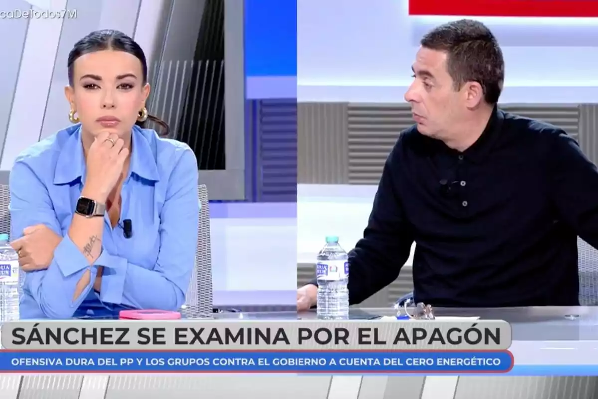 Antonio Naranjo y Sarah Santaolalla están sentadas en 'En boca de todos', una mujer con camisa azul y un hombre con camisa oscura, ambos con botellas de agua sobre la mesa y un rótulo en la parte inferior que menciona un tema político.