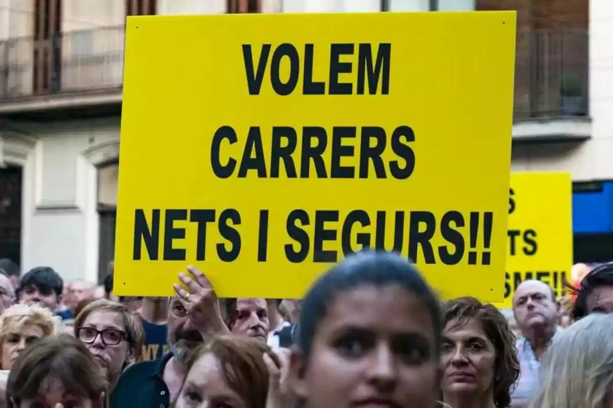 Un grupo de personas en una manifestación sosteniendo un cartel amarillo con un mensaje en catalán.
