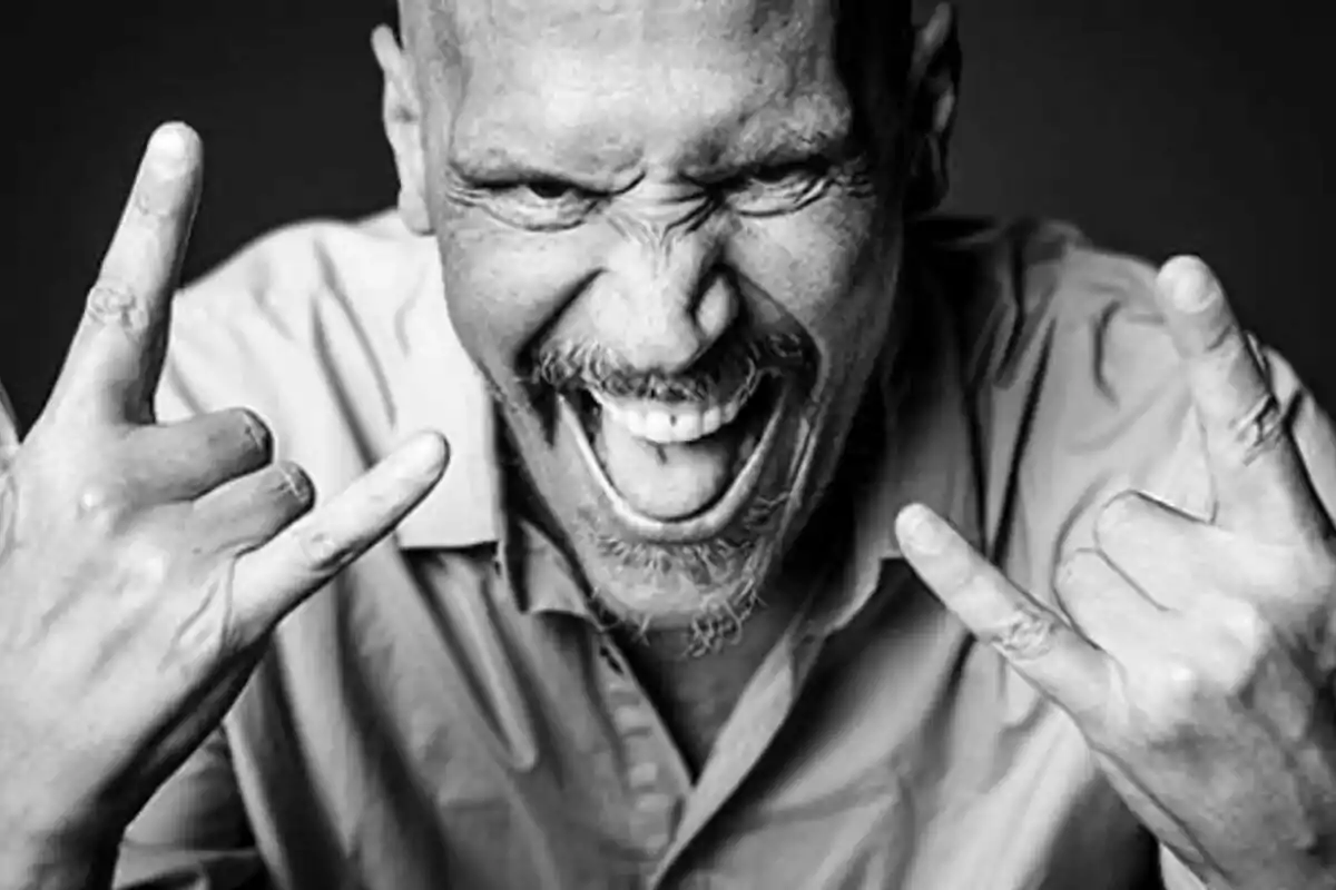 Sergio Peris-Mencheta calvo con barba haciendo el gesto de los cuernos con ambas manos y sonriendo en blanco y negro.