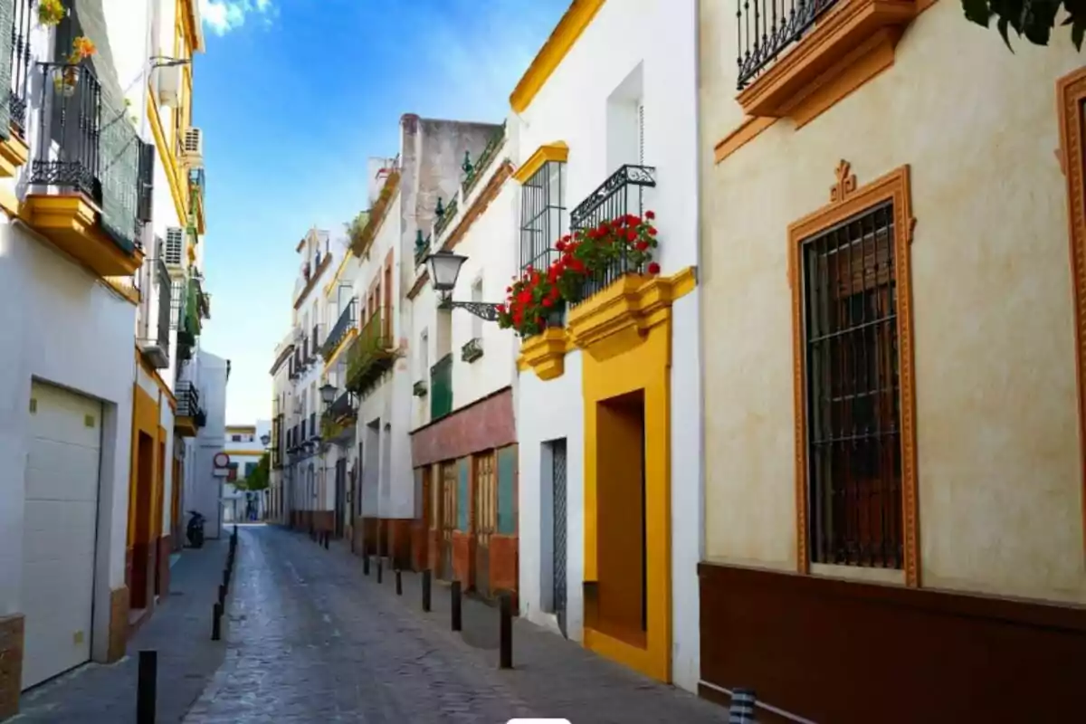 Una calle estrecha y pintoresca con edificios de colores brillantes y balcones adornados con flores.