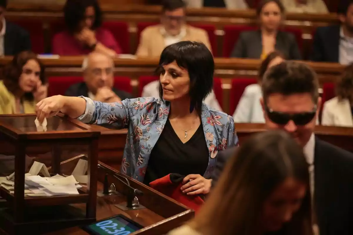 Plano medio de Sílvia Orriols votando en el Parlament de Catalunya con la barretina de su abuelo en su mano izquierda