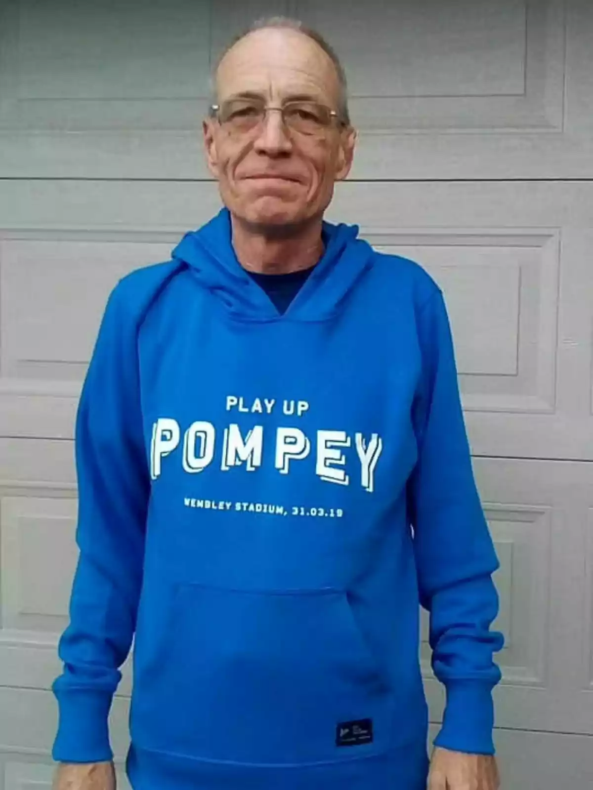 Simon Charles Dorante-Day con gafas y una sudadera azul que dice Simon Charles Dorante-Day con gafas y una sudadera azul que dice