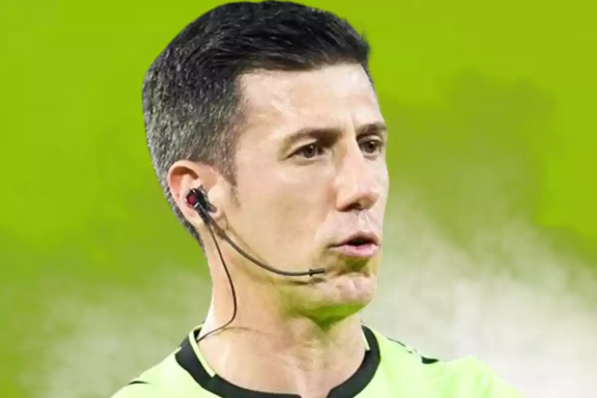 Un árbitro de fútbol con auricular y micrófono en un fondo verde.