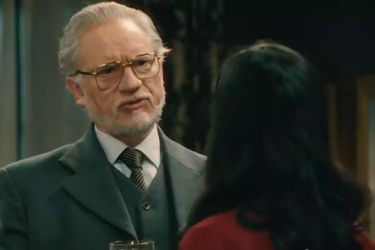 Damián hablando con una mujer de cabello largo y oscuro en un ambiente interior elegante. Captura de 'Sueños de libertad' Damián hablando con una mujer de cabello largo y oscuro en un ambiente interior elegante. Captura de 'Sueños de libertad'