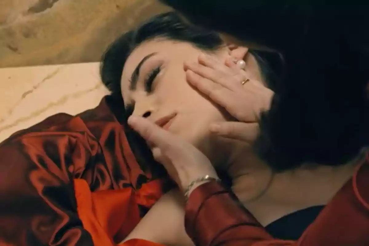 María recostada con los ojos cerrados mientras otra persona le sostiene el rostro con delicadeza. Captura de 'Sueños de libertad'