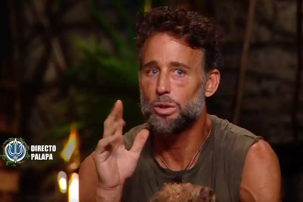 Álvaro Muñoz Escassi está hablando gesticulando con la mano en un entorno que parece una jungla o un set de televisión, con un logotipo en la esquina que dice Álvaro Muñoz Escassi está hablando gesticulando con la mano en un entorno que parece una jungla o un set de televisión, con un logotipo en la esquina que dice
