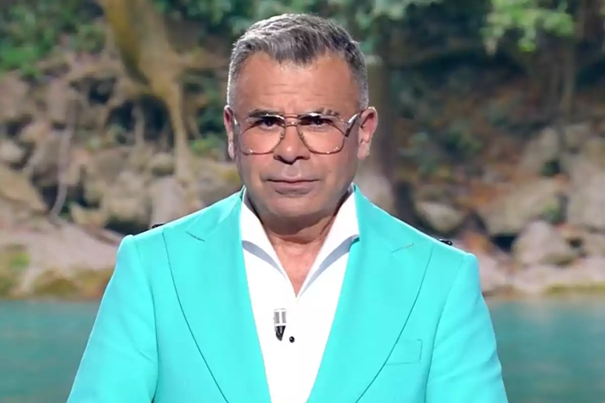 Jorge Javier Vázquez lleva un traje azul claro y una camisa blanca con un fondo de naturaleza. Captura de 'Supervivientes'