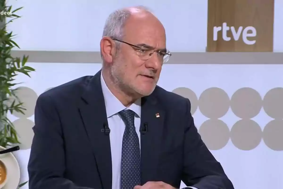 Un hombre con gafas y barba canosa está sentado en un estudio de televisión con el logo de RTVE visible al fondo.