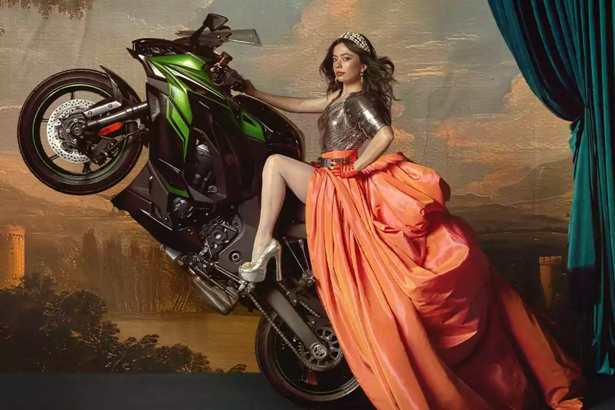 Anna Castillo con un vestido elegante y una armadura está montada en una motocicleta verde en una pose dramática frente a un fondo pintoresco en Su Majestad.