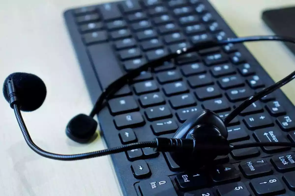 Un teclado de ordenador con unos auriculares encima