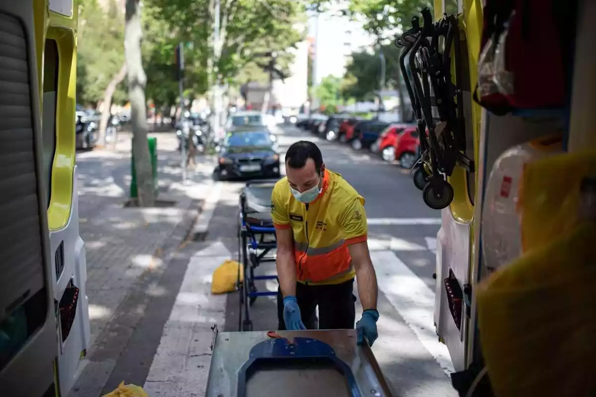 Un técnico del Sistema de Emergencias Médicas (SEM) de la Generalitat de Cataluña mete una camilla en una ambulancia durante un servicio