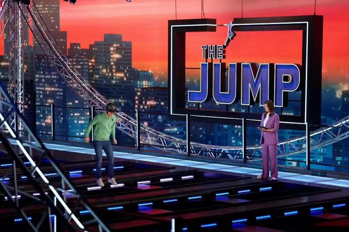 Fotografía de una persona con casco participando en un programa de televisión llamado The Jump, Salta en España, mientras una presentadora observa.