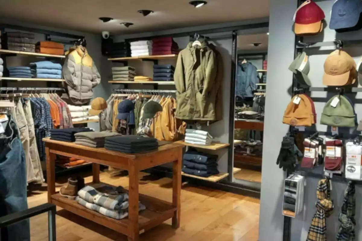 Una tienda de ropa con estantes llenos de prendas dobladas, chaquetas colgadas, gorras y bufandas en exhibición, todo organizado en un ambiente acogedor con un suelo de madera. Una tienda de ropa con estantes llenos de prendas dobladas, chaquetas colgadas, gorras y bufandas en exhibición, todo organizado en un ambiente acogedor con un suelo de madera.