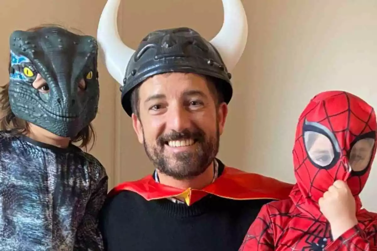 Imagen de Toni Cruanyes disfrazado con un gorro de vikingo y una capa roja, junto a un niño disfrazado de dinosaurio y otro de Spiderman