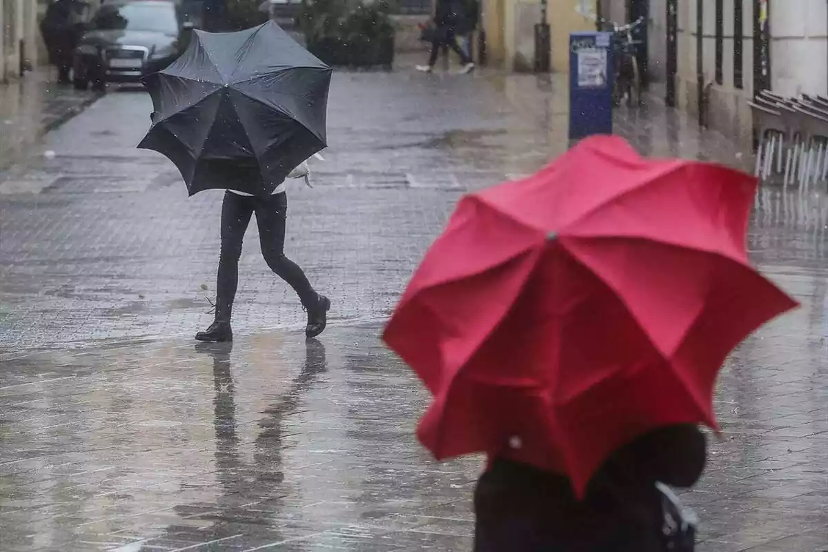 Dos personas con paraguas en medio de la calle durante una tormenta