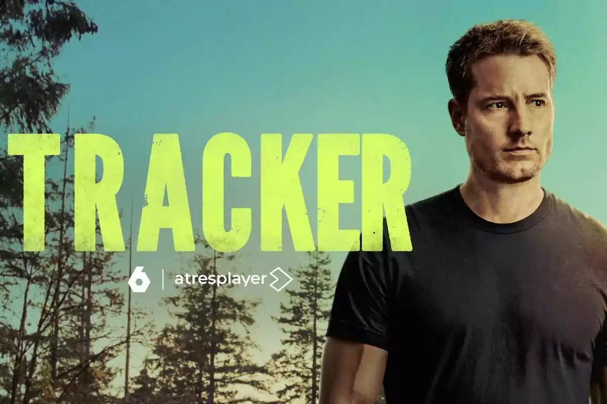 Justin Hartley de cabello corto y camiseta oscura de pie junto al título Tracker en letras grandes amarillas con un fondo de árboles y cielo azul
