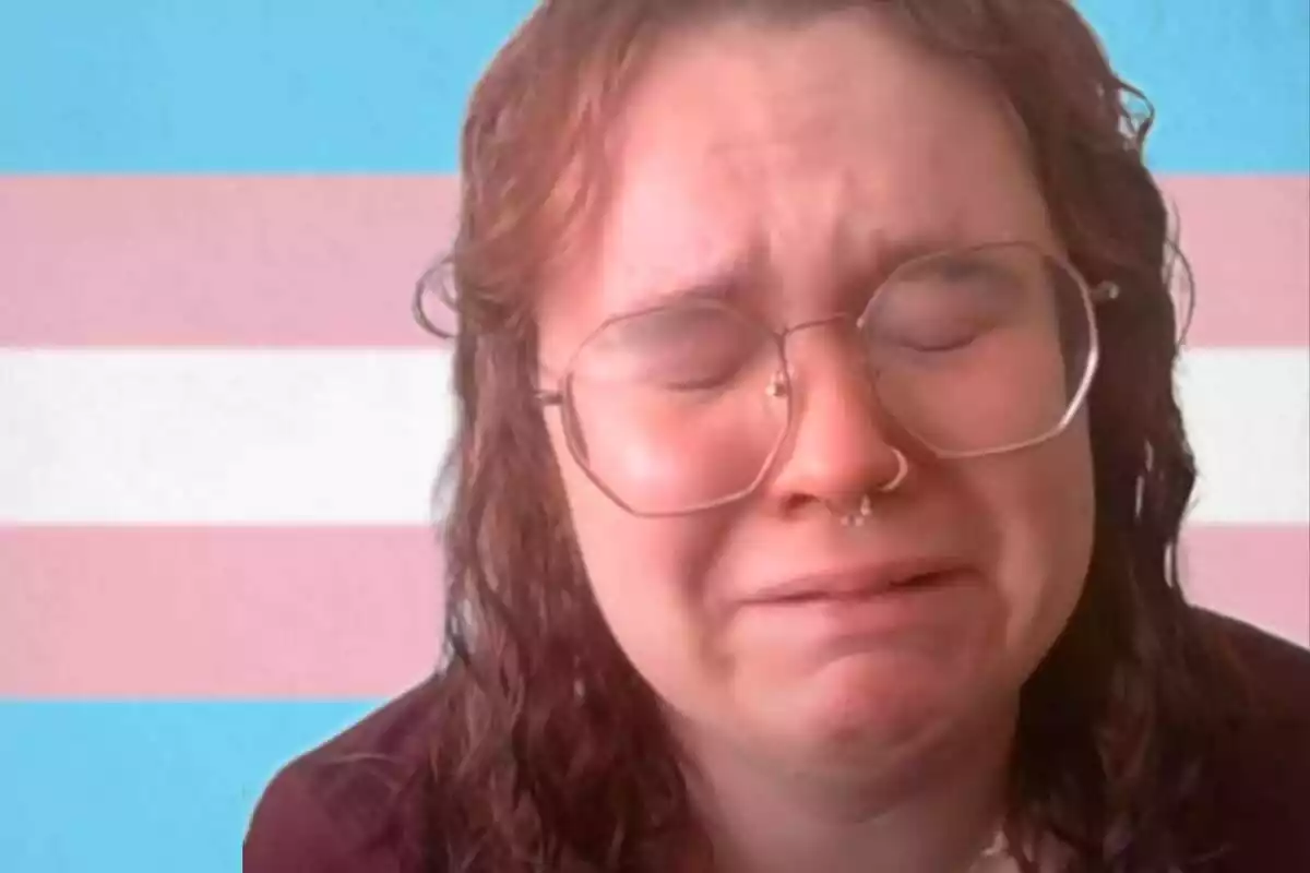 Primer plano de Prisha Mosley llorando con una bandera trans de fondo