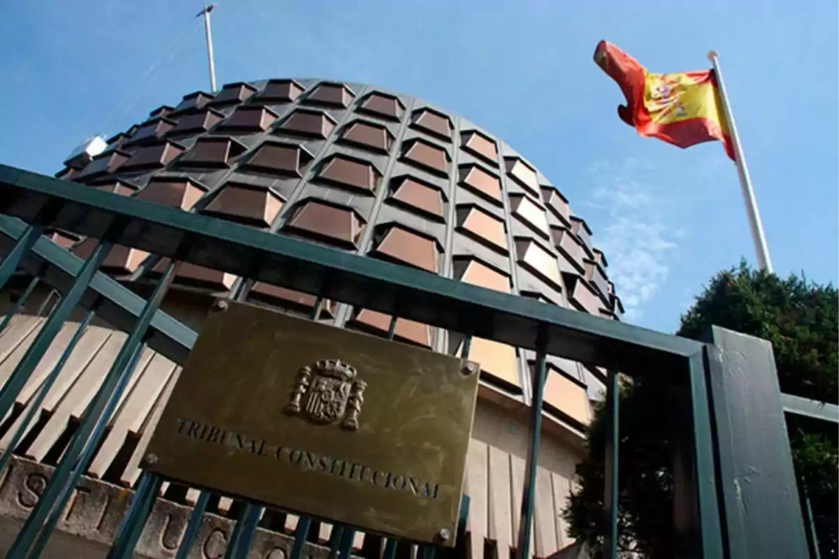 Edificio del Tribunal Constitucional de España con una bandera española ondeando al fondo. Edificio del Tribunal Constitucional de España con una bandera española ondeando al fondo.