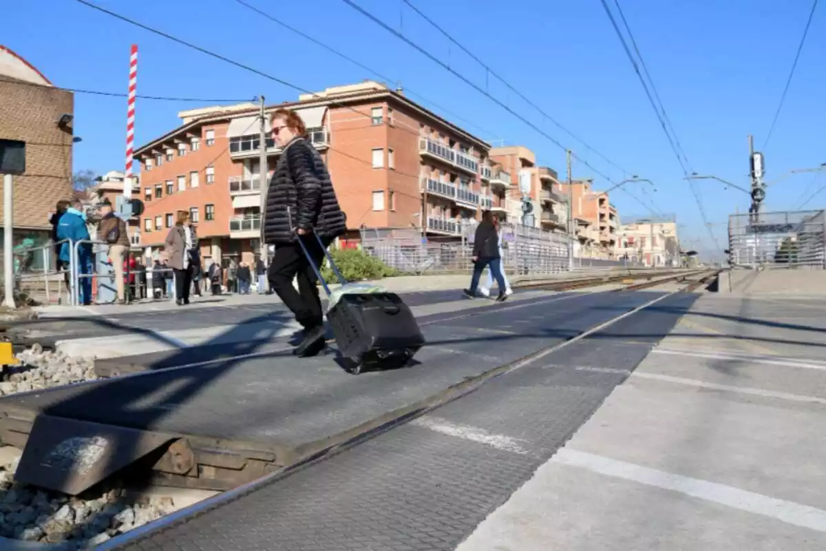 Una mujer cruzando el paso a nivel de las vías R2 en Montcada i Reixac (Barcelona)