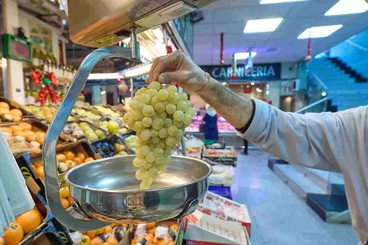 Imagen de una mujer pesando unas uvas en un mercado