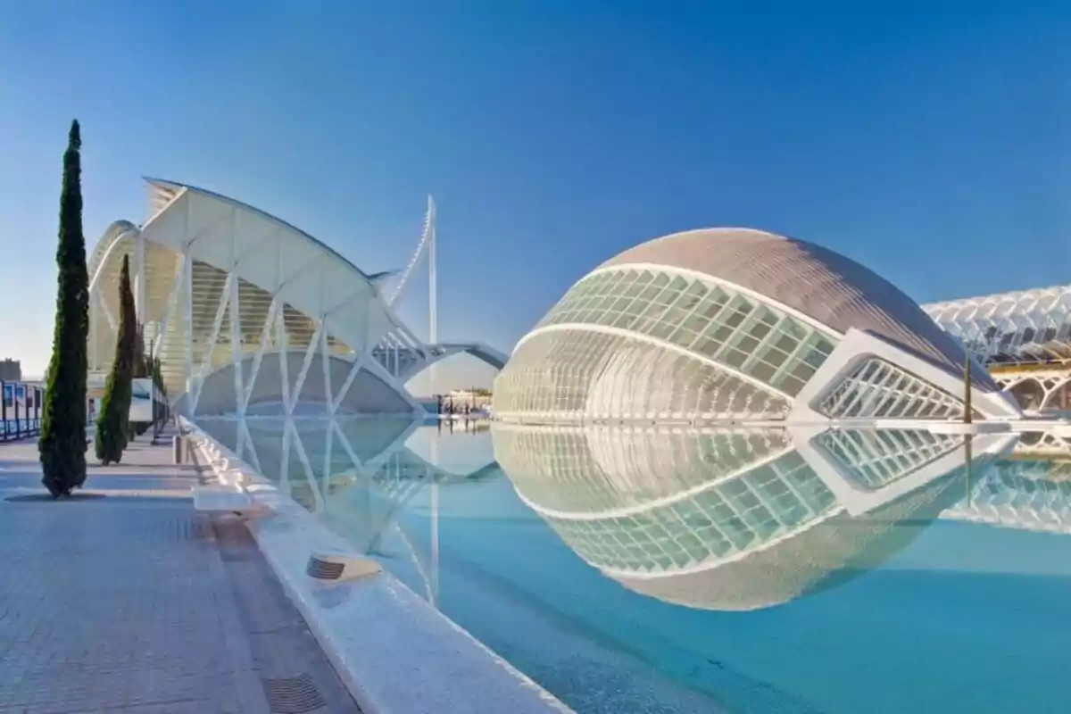 Edificios modernos con estructuras curvas reflejados en un estanque bajo un cielo despejado. Edificios modernos con estructuras curvas reflejados en un estanque bajo un cielo despejado.