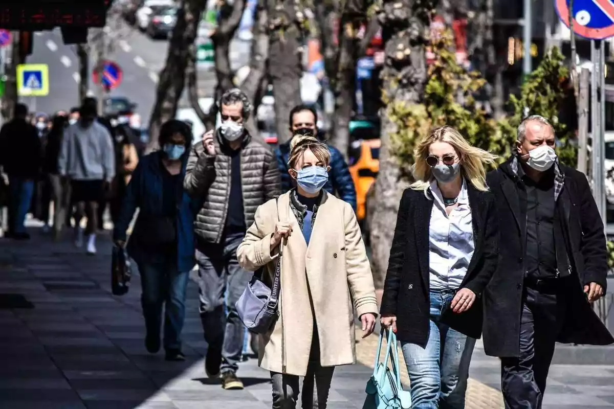 Varias personas en la calle llevando mascarilla