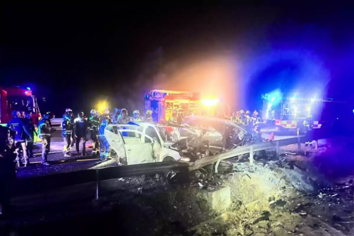 Accidente automovilístico nocturno con varios bomberos y vehículos de emergencia atendiendo la escena iluminada por luces de patrullas y camiones de bomberos Accidente automovilístico nocturno con varios bomberos y vehículos de emergencia atendiendo la escena iluminada por luces de patrullas y camiones de bomberos