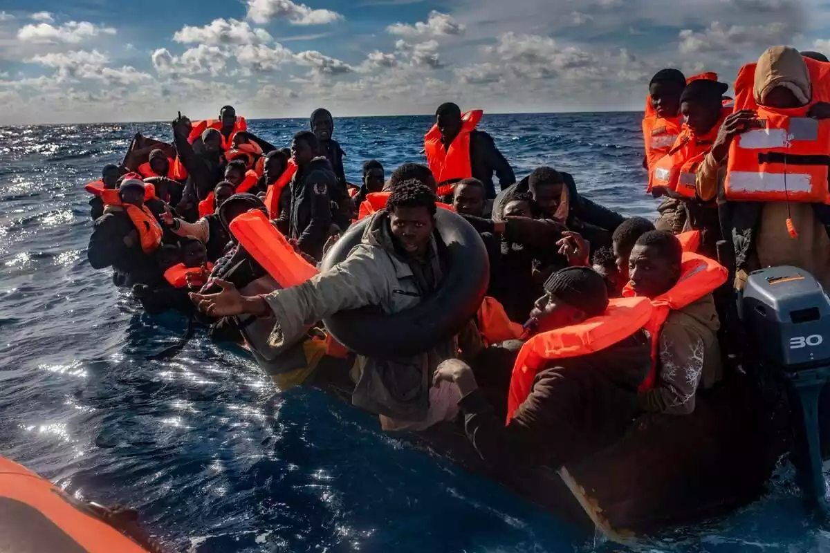 Varios migrantes viajando en un cayuco con chalecos salvavidas en el Mar Mediterráneo