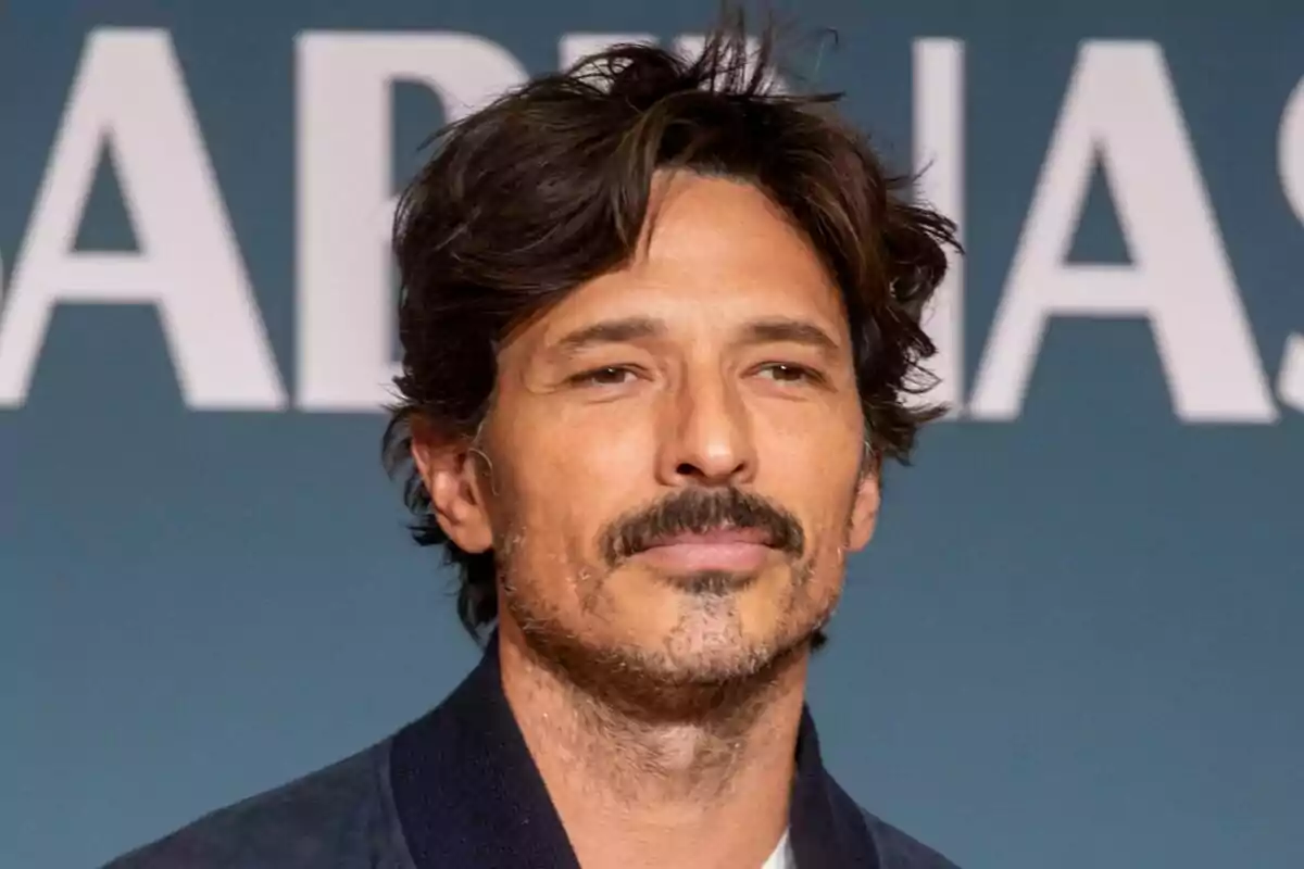 Andrés Velencoso con cabello oscuro y barba ligera frente a un fondo azul con letras blancas en la presentación de Regreso a las Sabinas.