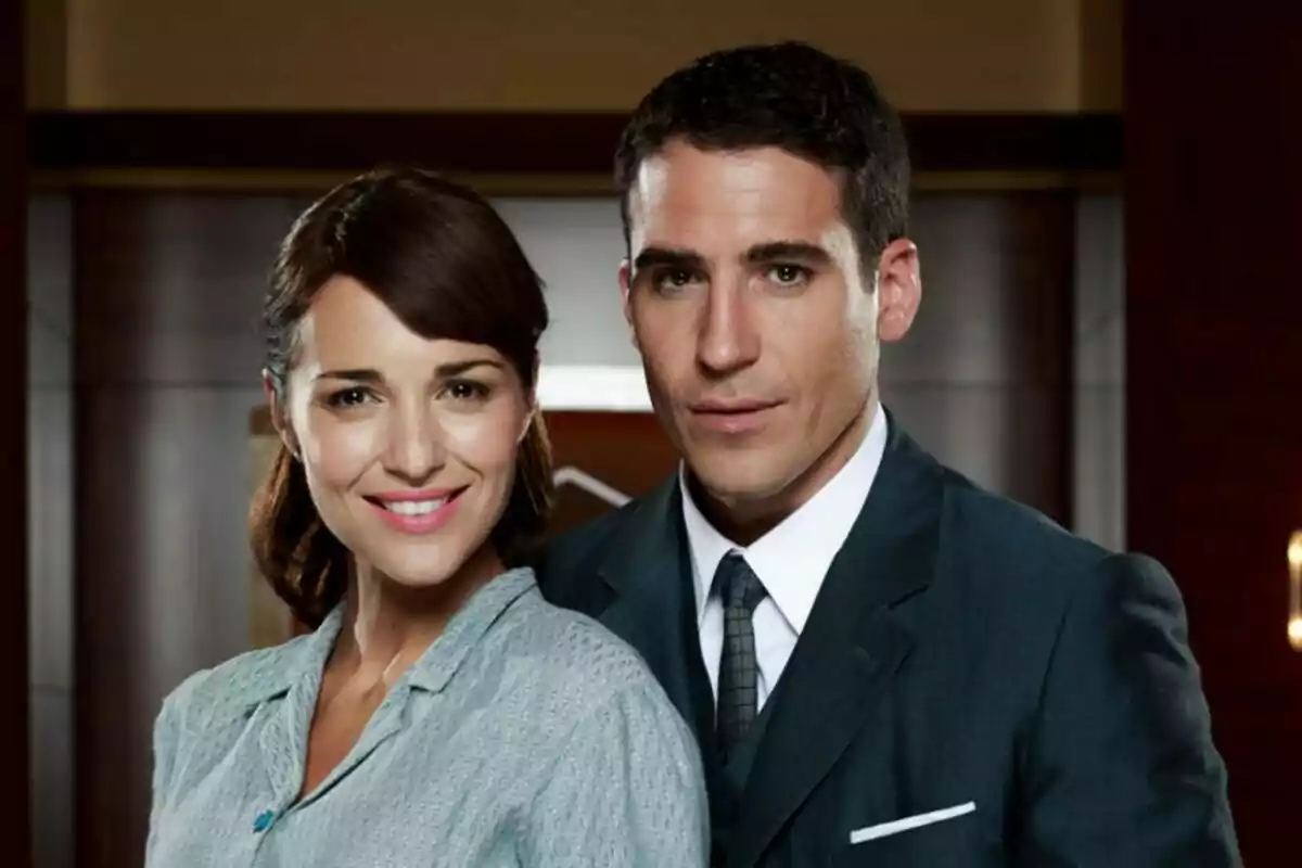 Paula Echevarría y Miguel Ángel Silvestre posan juntos, ambos sonrientes, en un entorno interior elegante en Velvet.