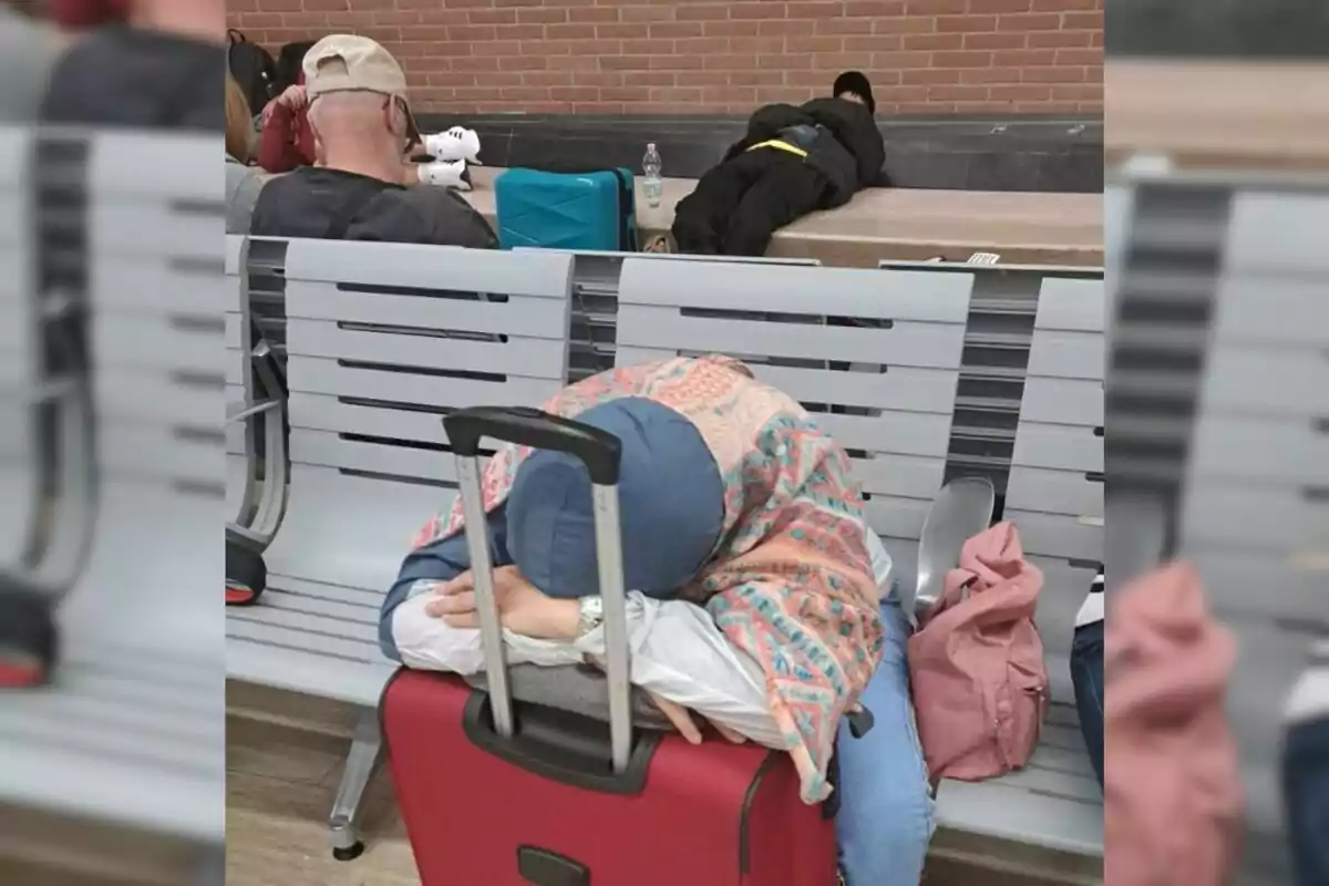 Personas durmiendo en una sala de espera con maletas y mochilas.