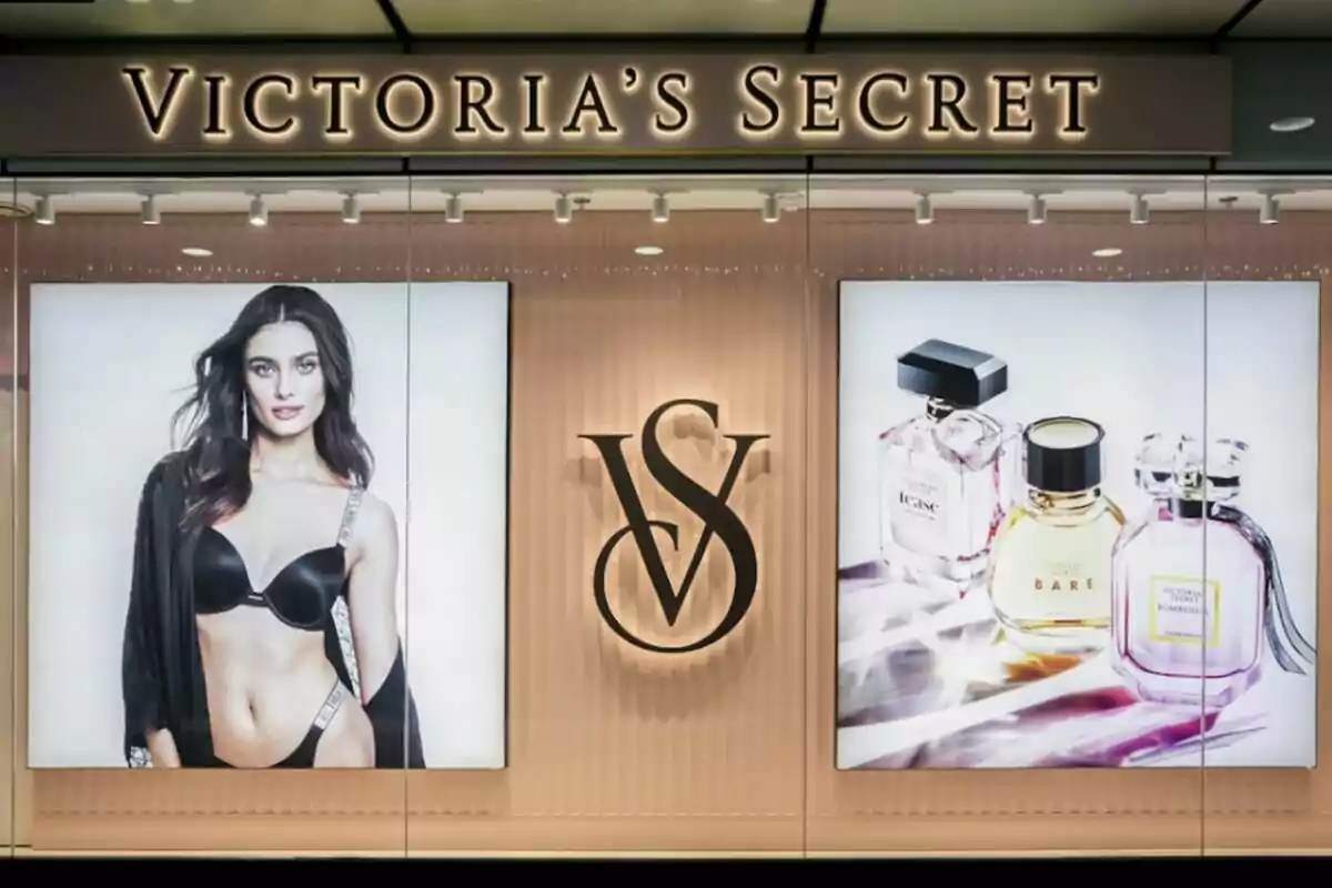 Escaparate de Victoria's Secret con una modelo en lencería a la izquierda, el logotipo de la marca en el centro y varios frascos de perfume a la derecha. Escaparate de Victoria's Secret con una modelo en lencería a la izquierda, el logotipo de la marca en el centro y varios frascos de perfume a la derecha.