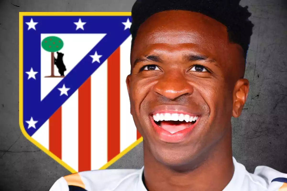 Un hombre sonriente frente al escudo del Atlético de Madrid.