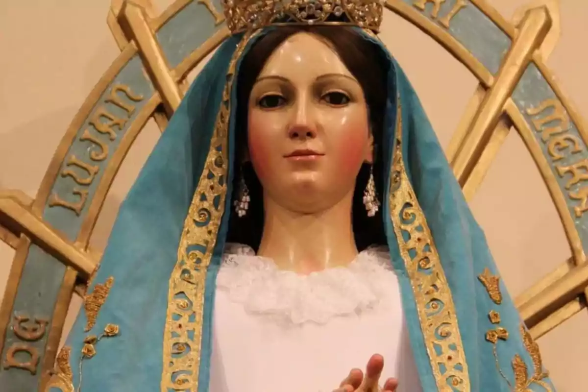 Una estatua religiosa con manto azul y detalles dorados, con una corona en la cabeza.