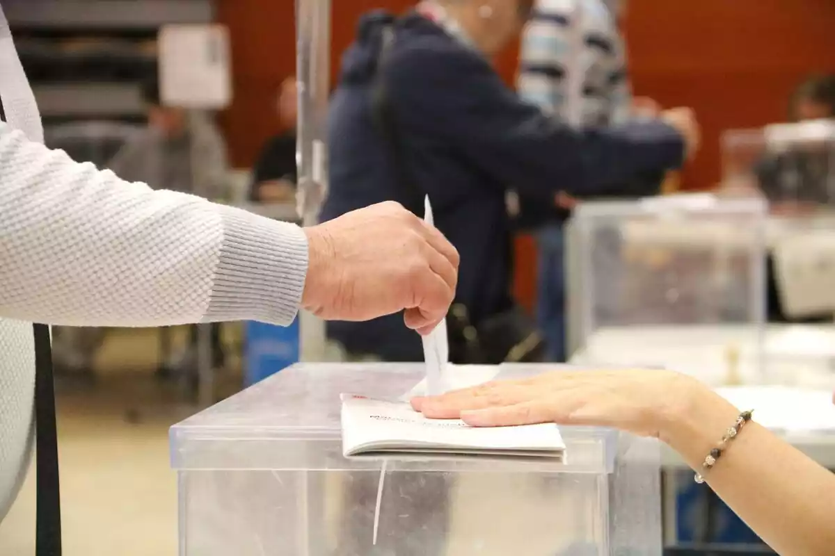 Imagen de una mano introduciendo un voto en una urna en las elecciones catalanas de 2024