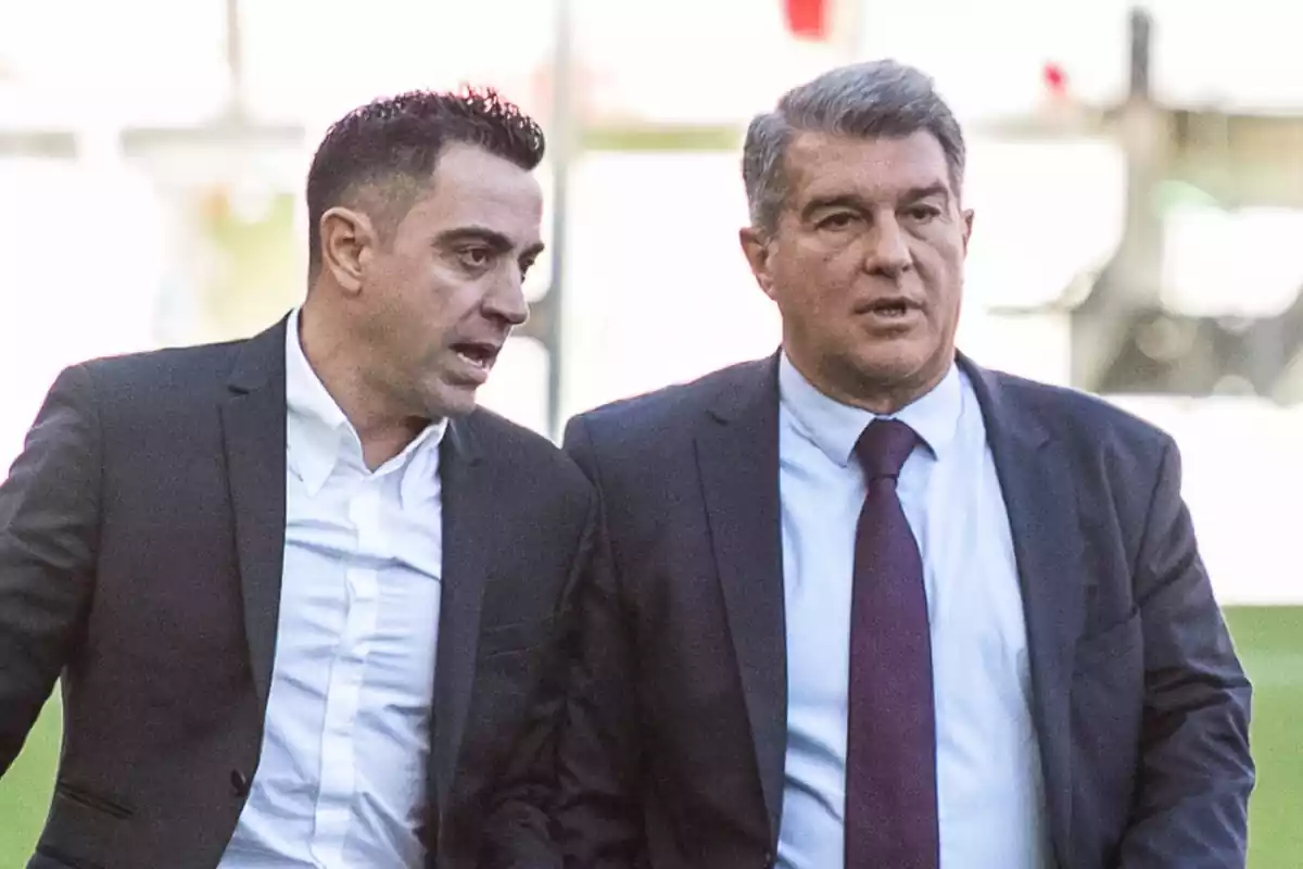 Joan Laporta y Xavi Hernández caminando juntos vestidos de traje