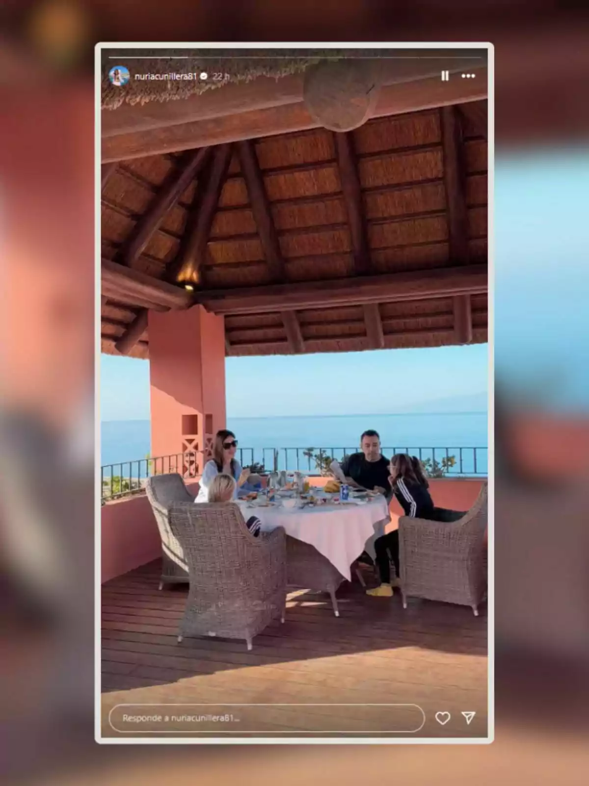 Un grupo de personas disfruta de una comida al aire libre en una terraza con vista al mar, bajo un techo de madera y paja. Un grupo de personas disfruta de una comida al aire libre en una terraza con vista al mar, bajo un techo de madera y paja.