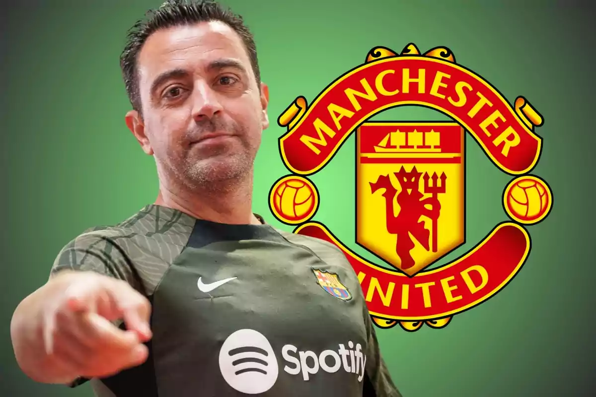 Un hombre con una camiseta de fútbol verde oscuro señala hacia adelante con el logo del Manchester United de fondo.