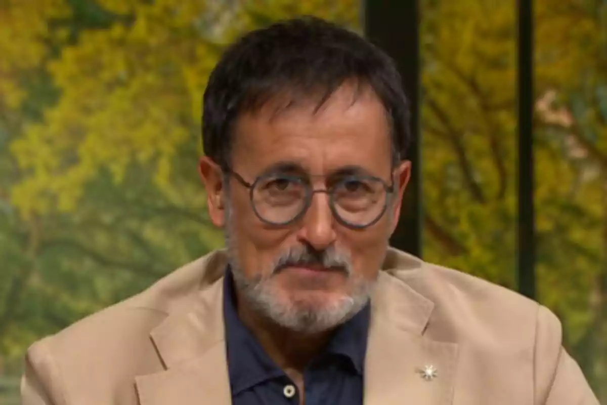 Fotografía de Xavier Grasset con gafas y barba, vestido con una chaqueta beige y camisa oscura, con un fondo de árboles verdes en La Selva de TV3.