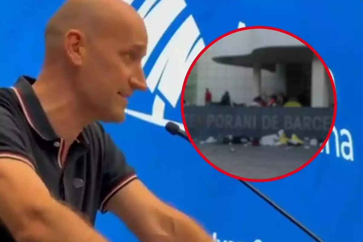 Un hombre calvo con una camiseta oscura habla frente a un micrófono con un fondo azul, mientras un recuadro muestra una escena exterior con personas y objetos dispersos frente a un edificio.