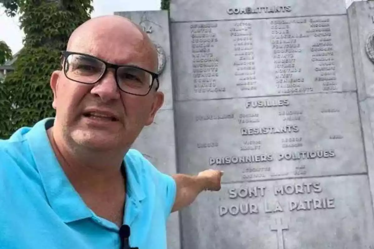 Primer plano de Xavier Rius señalando una placa conmemorativa a los caídos en la batalla de Bastogne, Bélgica, en la II Guerra Mundial