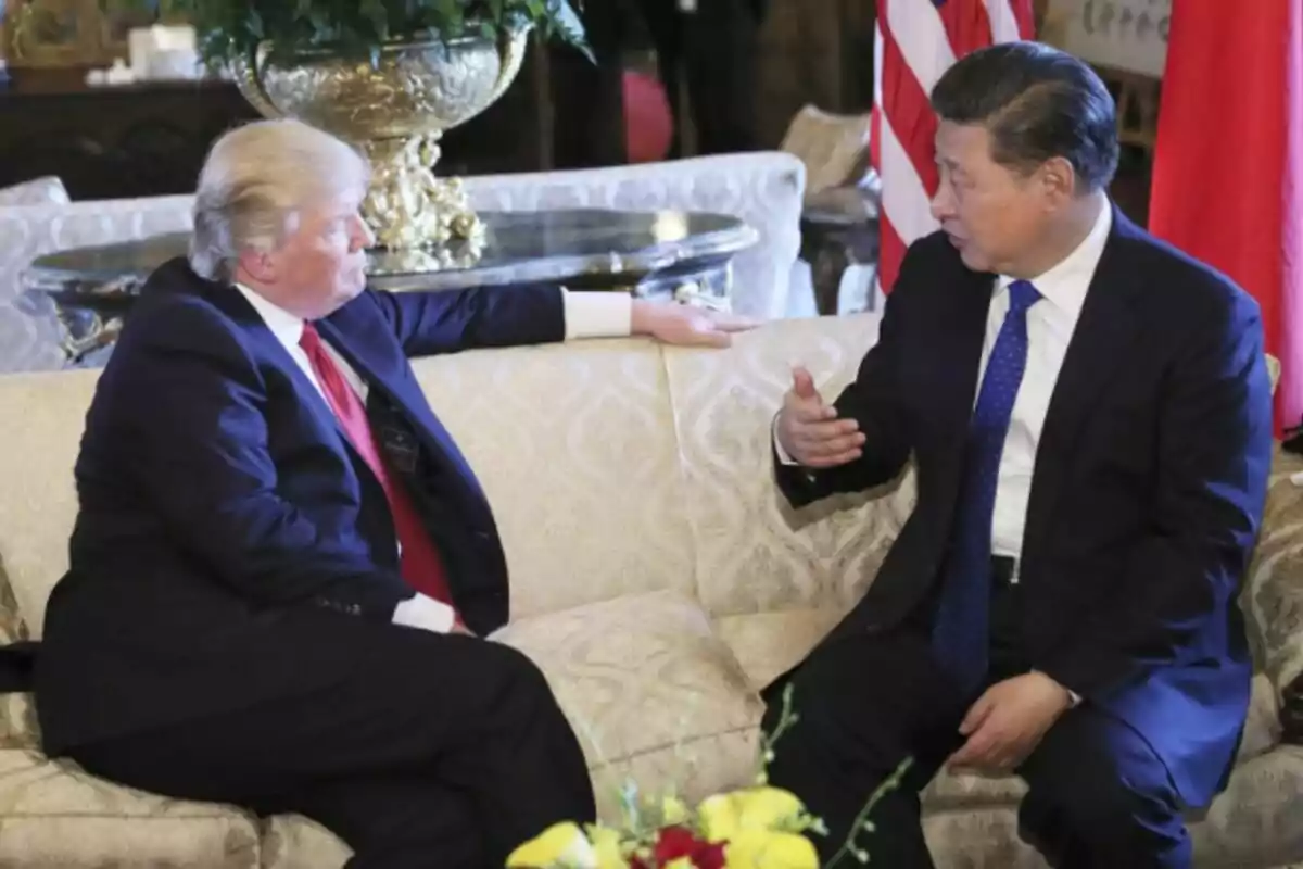 Dos hombres en trajes formales -que son Xi Jinping y Donald Trump- conversan sentados en un sofá elegante, con banderas y decoración de fondo. Dos hombres en trajes formales -que son Xi Jinping y Donald Trump- conversan sentados en un sofá elegante, con banderas y decoración de fondo.