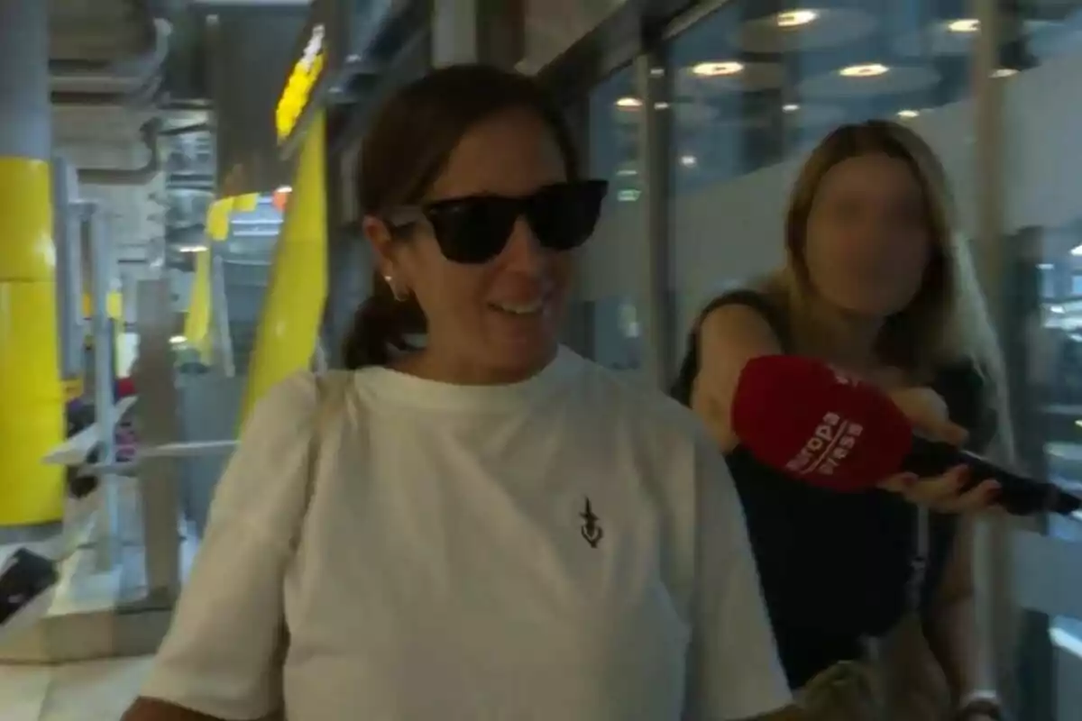 Anabel Pantoja con gafas de sol y camiseta blanca es entrevistada por una reportera que sostiene un micrófono rojo de Europa Press en un entorno urbano con elementos amarillos y grises. Captura de YouTube del 29 de julio de 2024 Anabel Pantoja con gafas de sol y camiseta blanca es entrevistada por una reportera que sostiene un micrófono rojo de Europa Press en un entorno urbano con elementos amarillos y grises. Captura de YouTube del 29 de julio de 2024