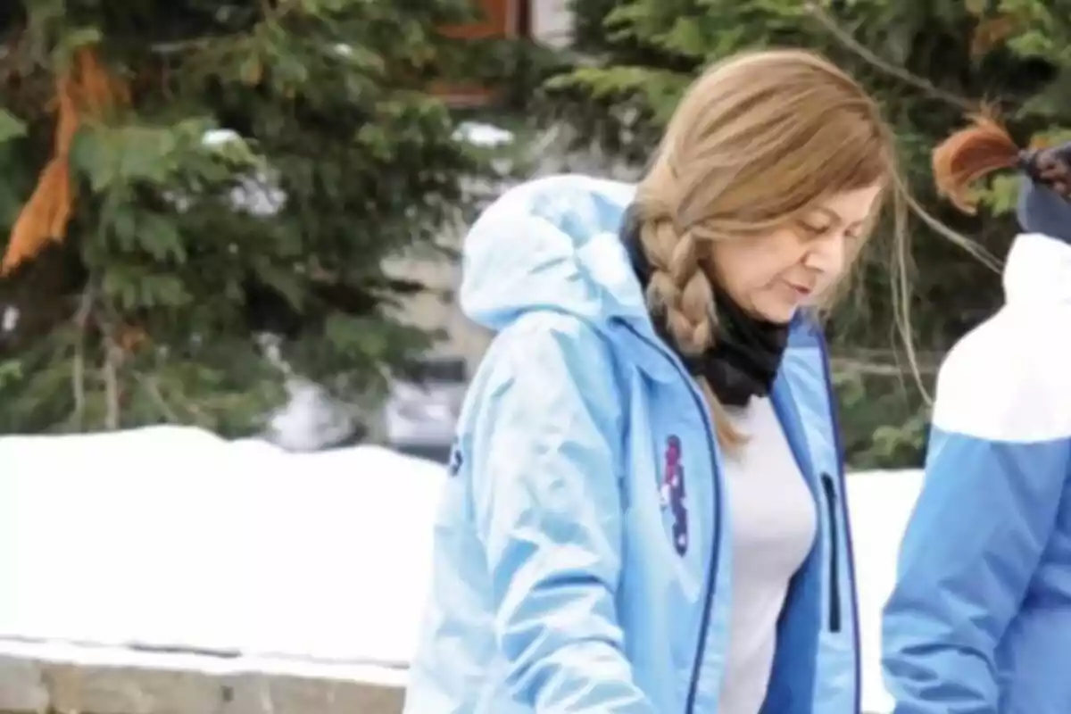 Laura Llopis con abrigo azul y trenza camina en un entorno nevado con árboles de fondo. Laura Llopis con abrigo azul y trenza camina en un entorno nevado con árboles de fondo.