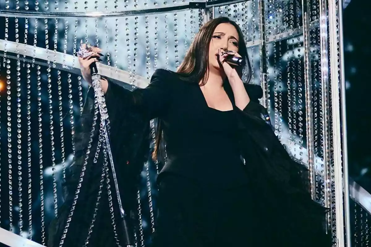 Yuval, representante de Israel en Eurovisión, canta en el escenario rodeada de cortinas de cristal y luces brillantes. Yuval, representante de Israel en Eurovisión, canta en el escenario rodeada de cortinas de cristal y luces brillantes.