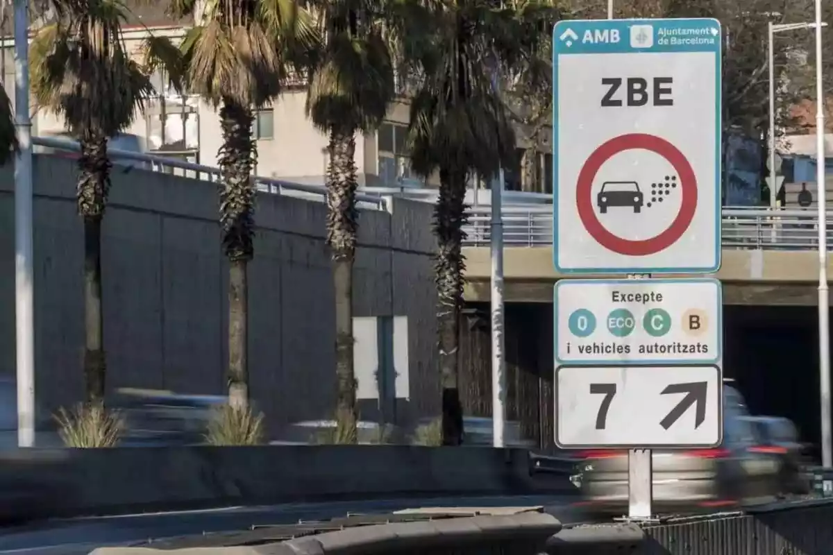 Imagen de un cartel de Zona de Bajas Emisiones y de fondo una carretera con varios coches pasando a alta velocidad